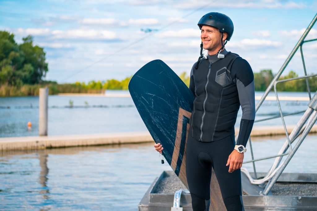 Smiling wakeboarder in wetsuit and helmet